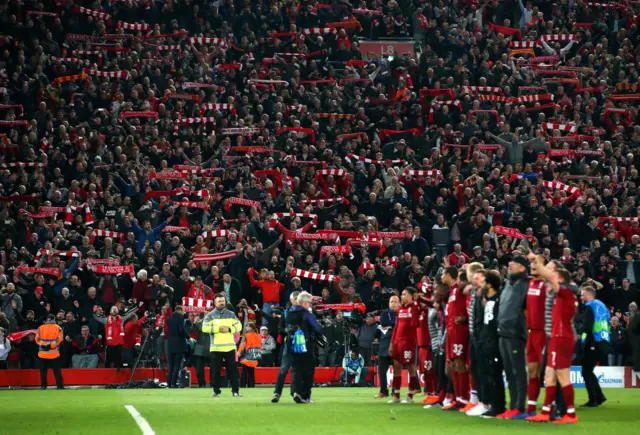 The crowd hold up scarves at Anfield