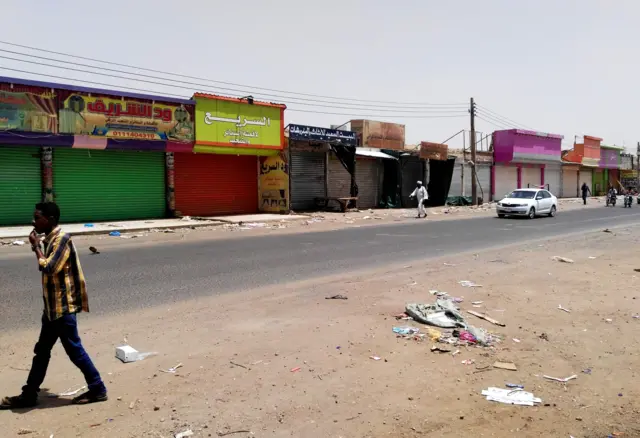 People walk in front of closed shops