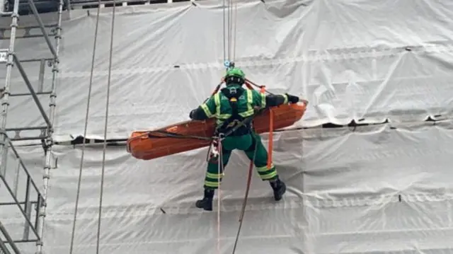 Stretcher being lowered with paramedic using ropes