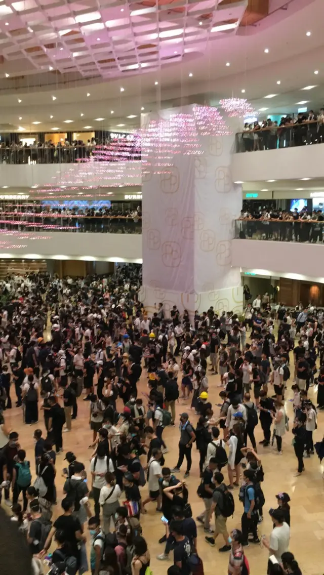 Hundreds of masked protesters stand around in Pacific Place shopping centre in Hong Kong