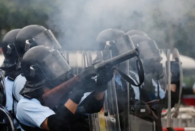 Police officer fires tear gas at protesters during a demonstration against a proposed extradition bill in Hong Kong