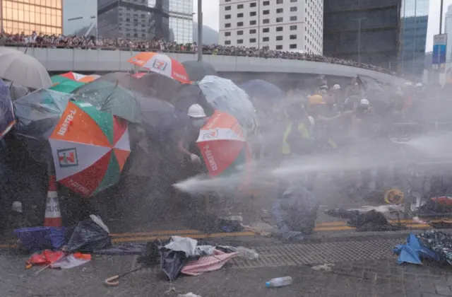 Protesters are hit by police water cannon during a demonstration against a proposed extradition bill in Hong Kong