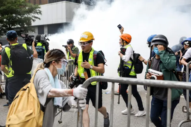 Protesters and members of the media react after police fired tear gas