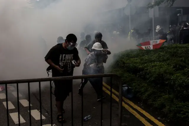 Protesters flee the area after police fired tear gas during demonstrations outside the Legislative Council Complex