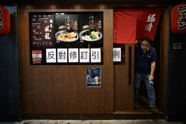 A man leaves a restaurant displaying a sign (in white) opposing a controversial plan to allow extraditions to the mainland in Hong Kong on June 11, 2019