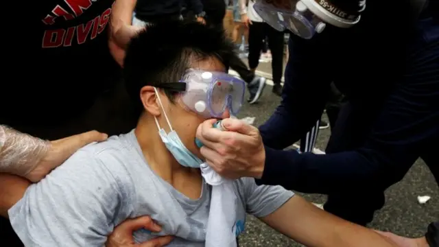 Protesters help a man during a demonstration against a proposed extradition bill where tear gas was fired, in Hong Kong, China June 12, 2019