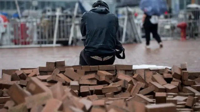 A man rests on a pile of bricks gathered by protesters during a rally against an extradition bill outside the Legislative Council in Hong Kong 12 June 2019