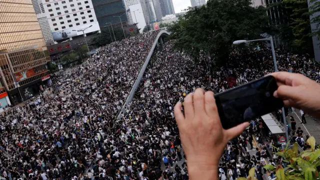 A man uses a mobile phone to record a protest against the proposed extradition bill in Hong Kong,