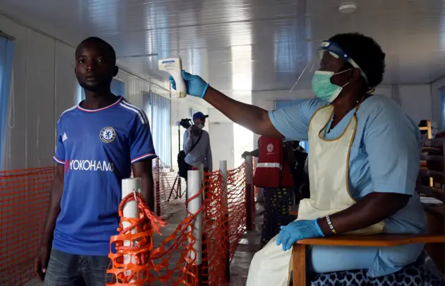 A health worker checks the temperature of a man in Mpondwe Health Screening Facility in Mpondwe, Uganda June 13, 2019.