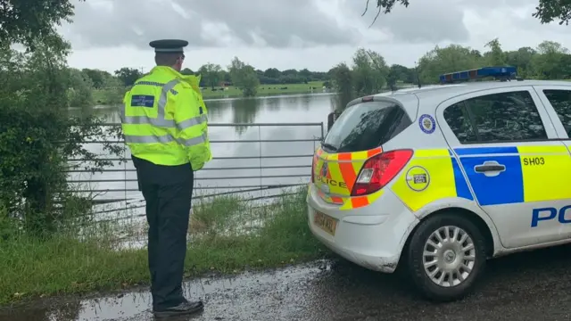 Police officer next to flooded field