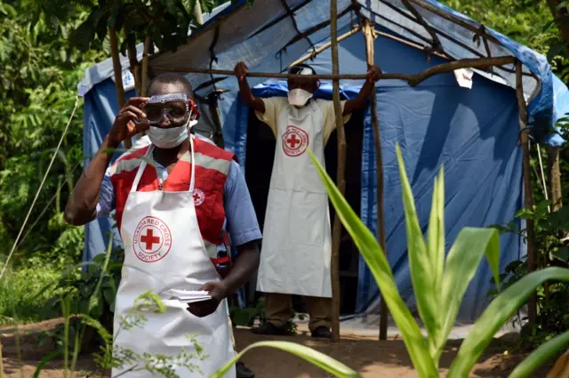 Health workers stand at a non-gazetted crossing point in the Mirami village, near the Mpondwe border check point between Uganda and the Democratic Republic of Congo on June 14, 2019.