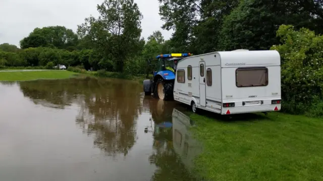 Tractor pulling caravan through standing water