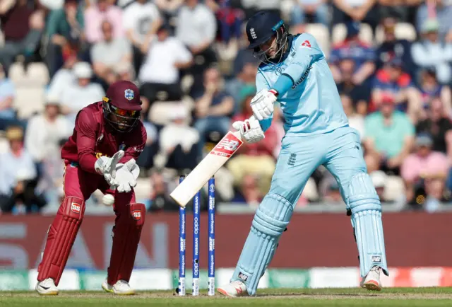 Joe Root (R) is watched by West Indies" wicketkeeper Shai Hope