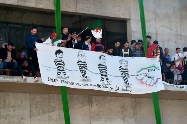 Protesters holding out banner of Bouteflika allies