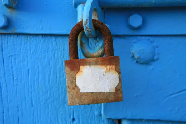 A close shot of a padlocked blue door