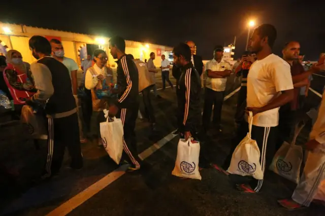 Migrants disembark the boat on the Tunisian coast.