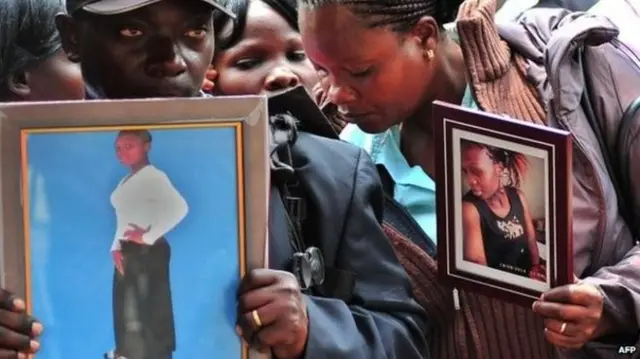 People hold photos of the loved ones they lost in the terror attack