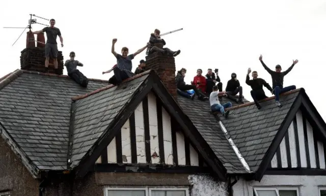 Fans sit on house roof to watch Liverpool victory parade