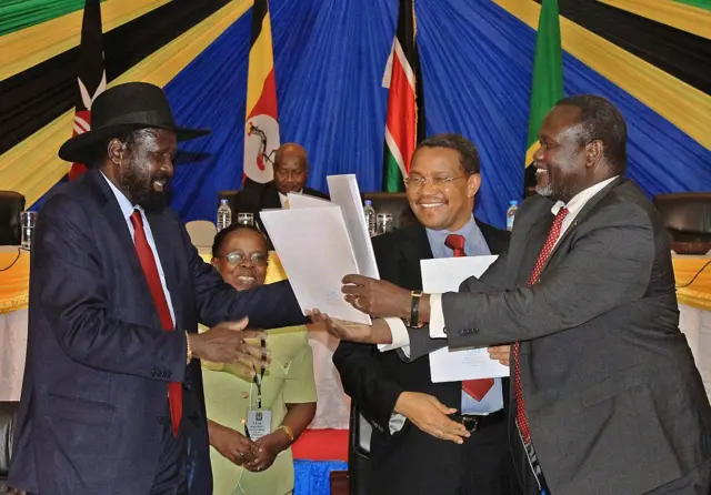 South Sudan's President Salve Kiir and rebel leader Riek Machar exchange signed peace deal documents in 2015