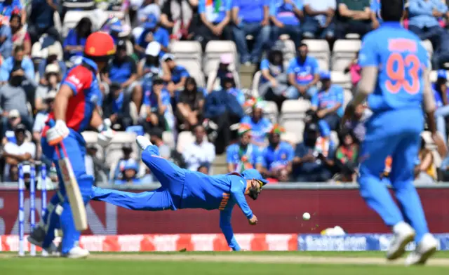 Virat Kohli (C) dives for an attempted catch during the 2019 Cricket World Cup group stage match between India and Afghanistan