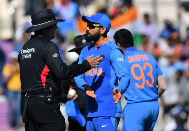 Virat Kohli (C) speaks with the umpire