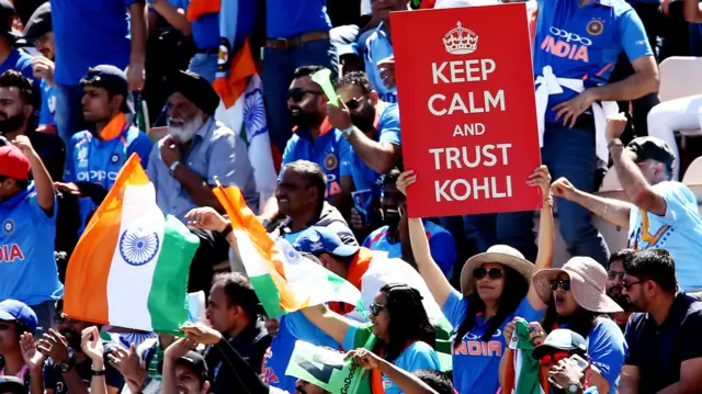 An India fan holds up a keep calm and trust Kohli sign