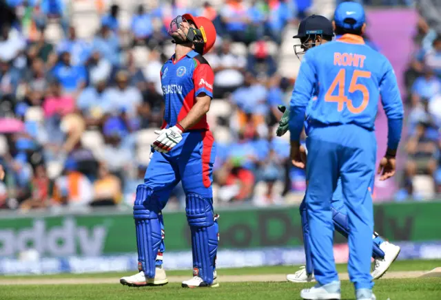 Rahmat Shah (L) reacts after being hit by a ball from a fielder