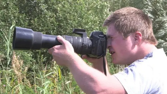 Oliver Hellowell takes some photographs with a large lens