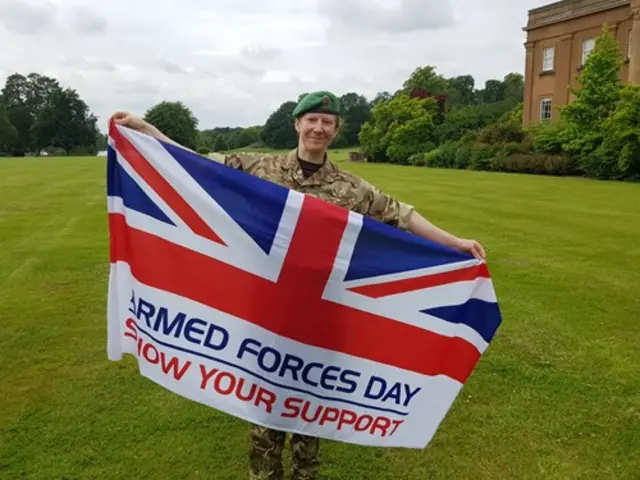 Major Louise Smith, officer commanding 63 Military Intelligence Company, with Armed Forces Day flag