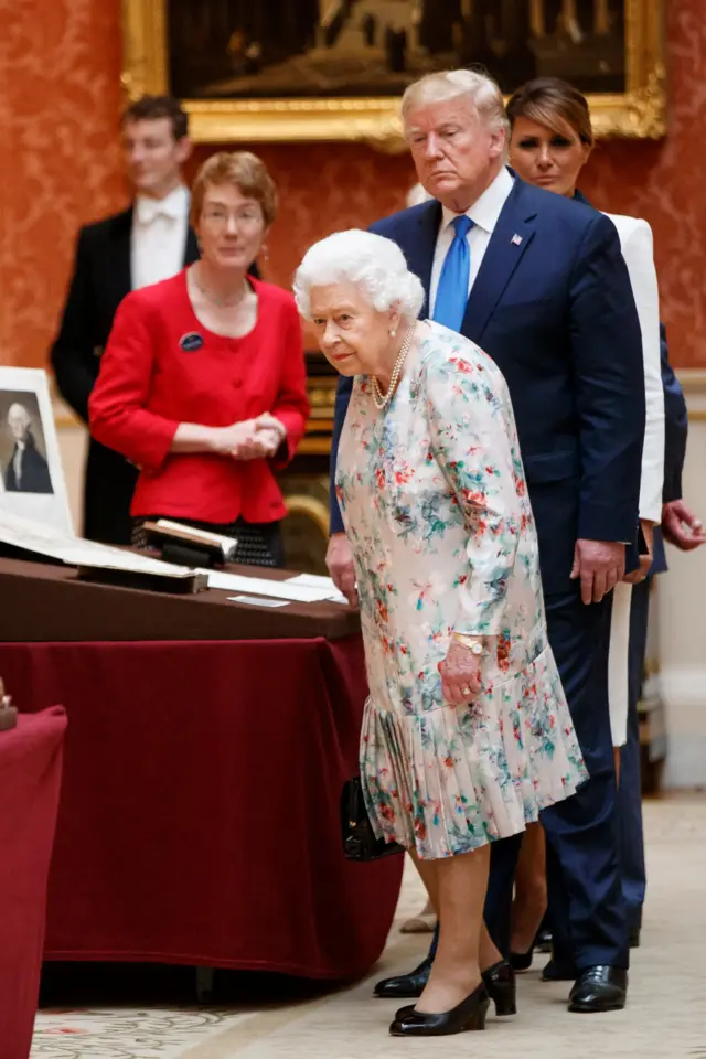 Britain"s Queen Elizabeth II (L) views a display of US items of the Royal collection with US President Donald Trump (C) and US First Lady Melania Trump (R) at Buckingham palace