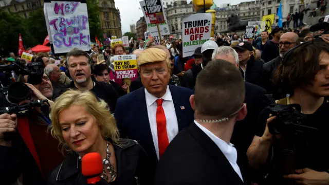 A man dressed as Donald Trump makes his way through protesters in Trafalgar Square