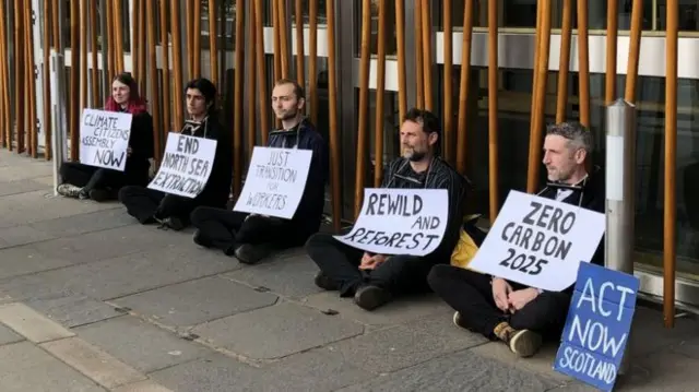 Five activists chained themselves by the neck to the facade of the Holyrood building