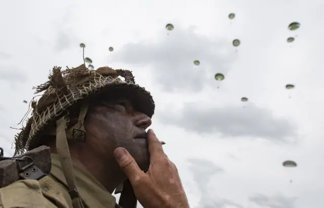 A man smokes a cigarette as he watches the parachute jump