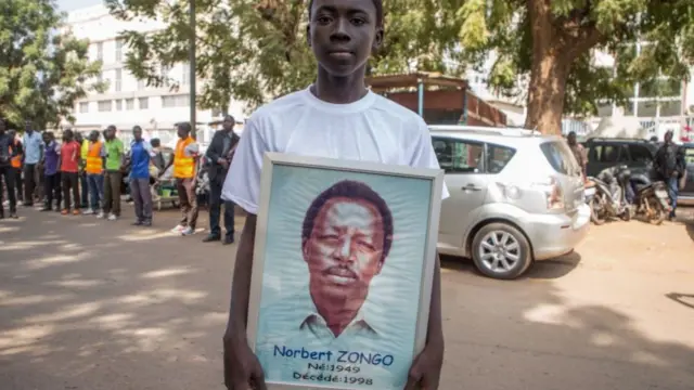 A man holds a portrait of Norbert Zongo as thousands of people take part in a demonstration in Ouagadougou, Burkina Faso, to mark the 20th anniversary of the assassination of Burkinabe investigative reporter Norbert Zongo - 13 December 2018