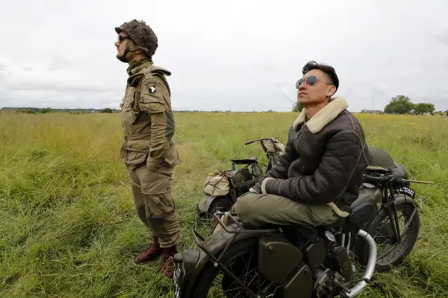 Two men in Second World War outfits watch the planes