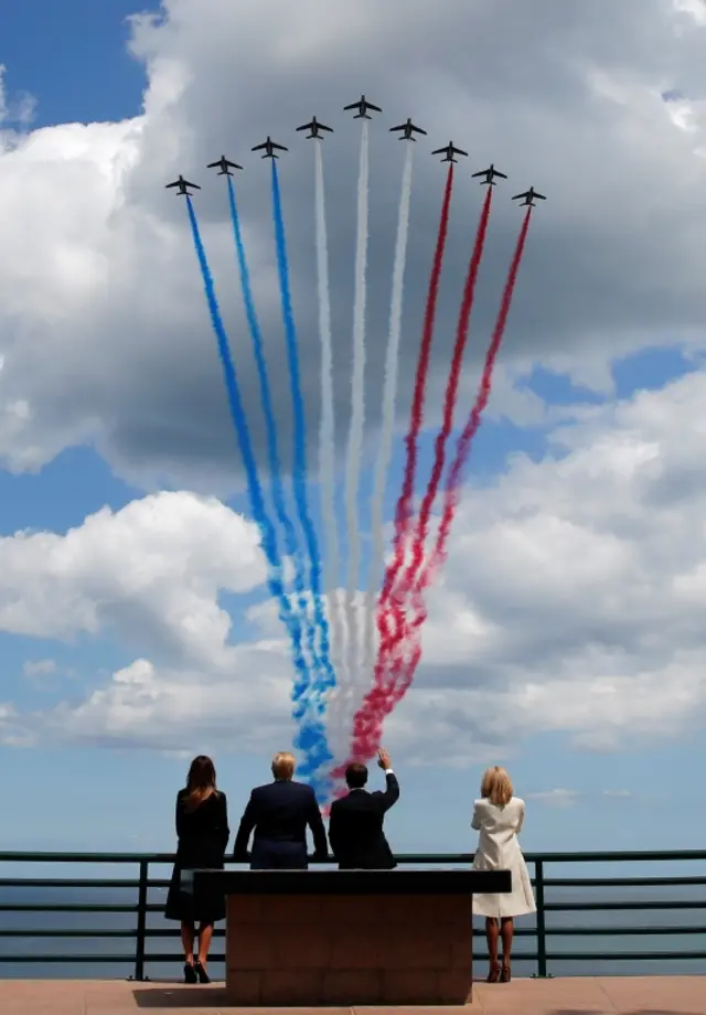 US President Trump and French President Macron look to flypasts with their wives