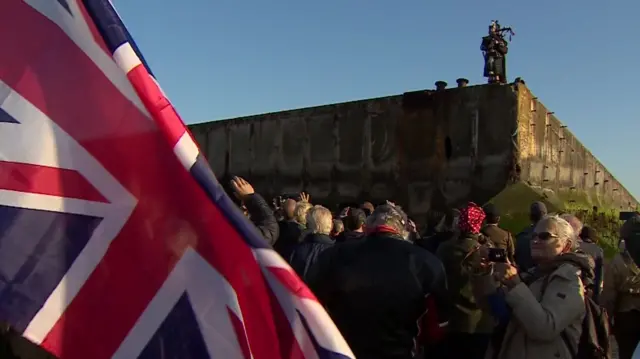 A lone piper on the Mulberry Harbour in the town of Arromanches