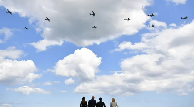 US President Trump, President Macron and their wives watch as aircrafts fly over after a French-US ceremony at the Normandy American Cemetery