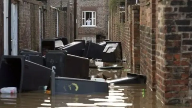 Black bins floating in flood water