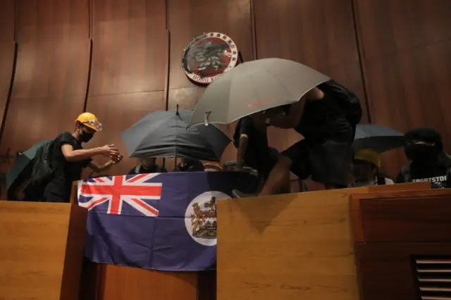 Protesters with the old British colonial flag inside the parliament