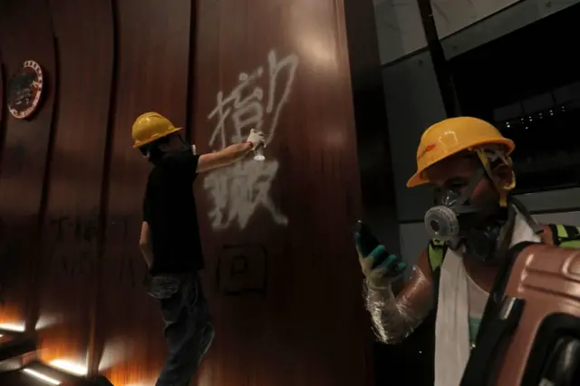 A protesters sprays graffiti onto the wall of the parliament chamber