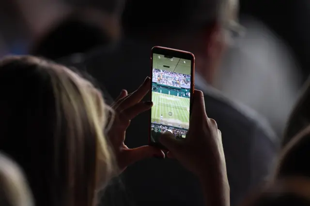A spectator takes a picture on their phone on Centre Court
