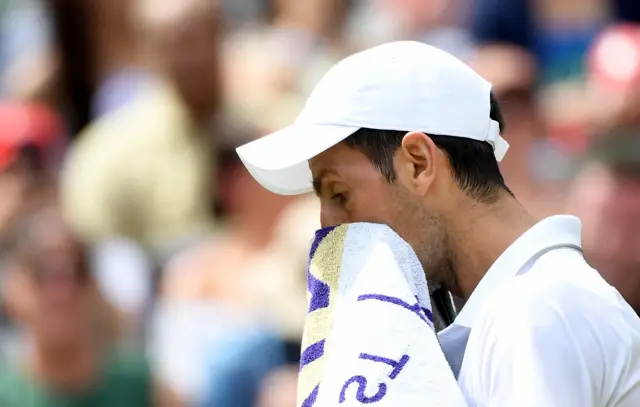 Novak Djokovic wipes his face with a towel