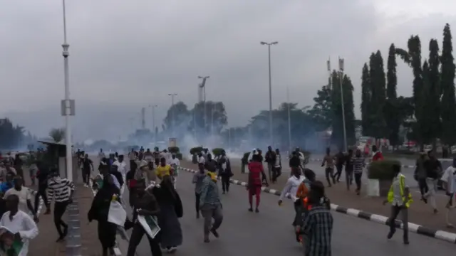 Tear gas is visible behind Shia protesters on the streets of Abuja