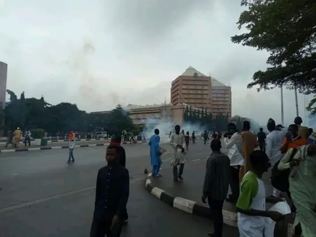 Tear gas is visible behind Shia protesters on the streets of Abuja