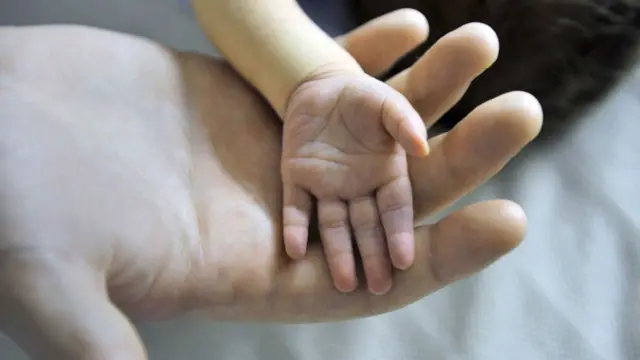 Baby's hand in parent's hand