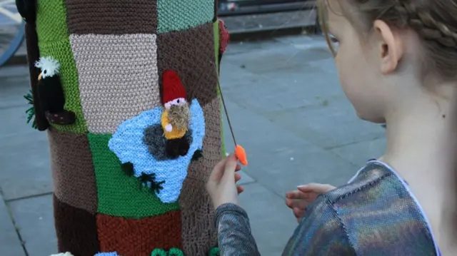 A young girl touching one of the woolly creations