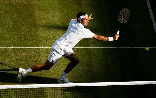 Roger Federer gets to a low ball near the net to flick an unlikely winner