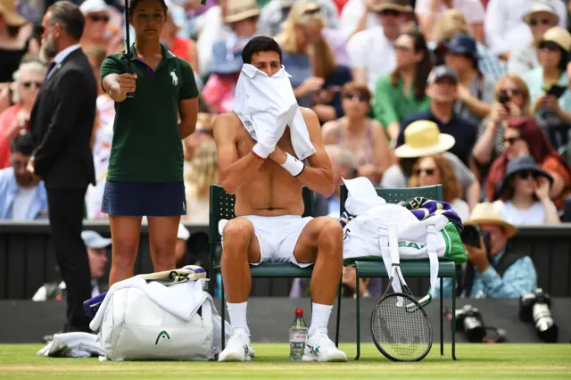 Novak Djokovic changes his shirt at the change of ends