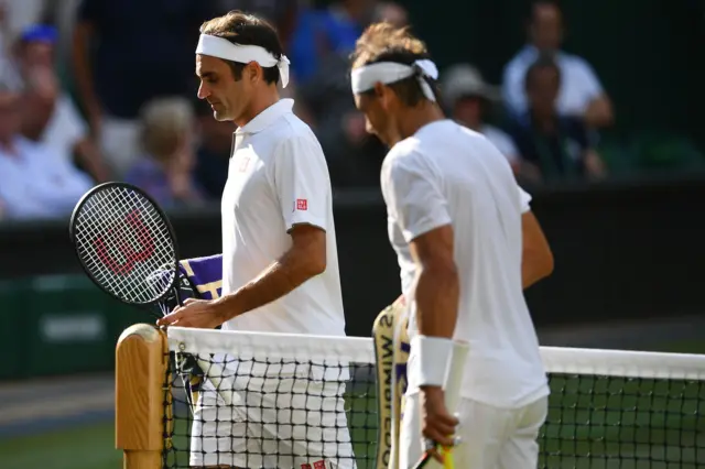 Roger Federer and Rafael Nadal pass each other at the net after the second set